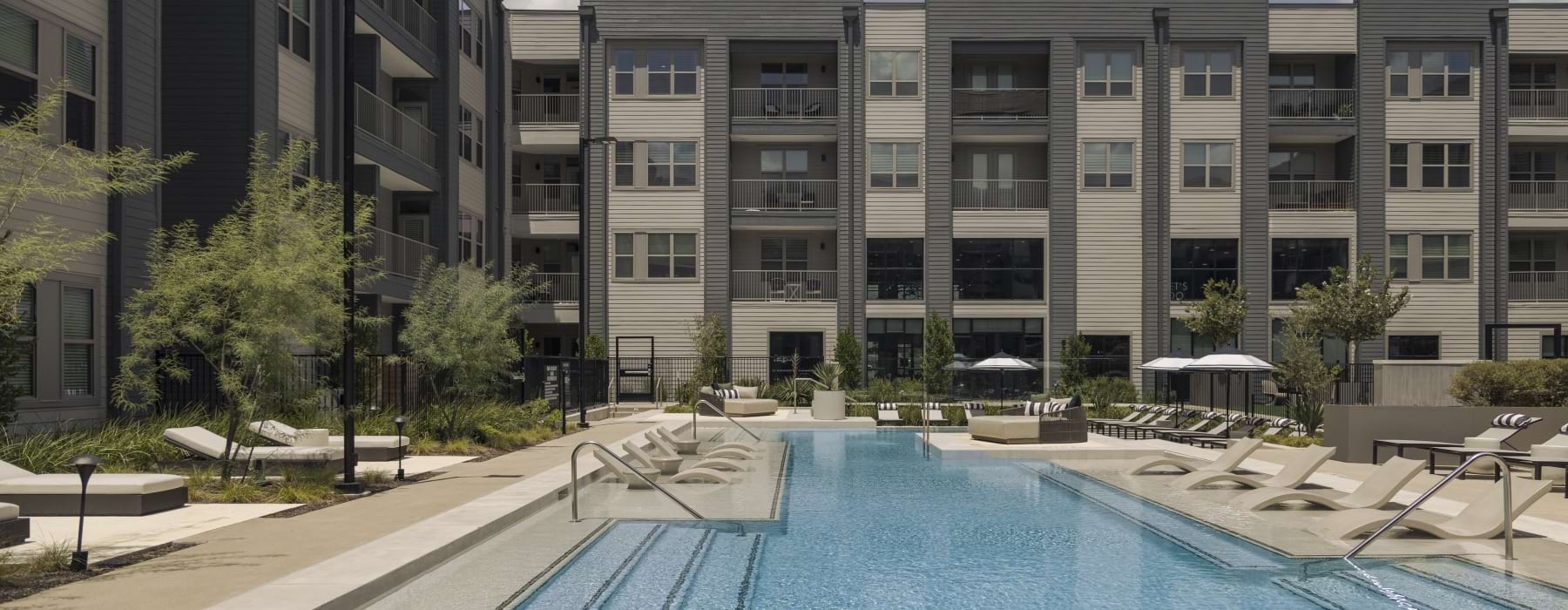 a swimming pool in a courtyard with lounge chairs